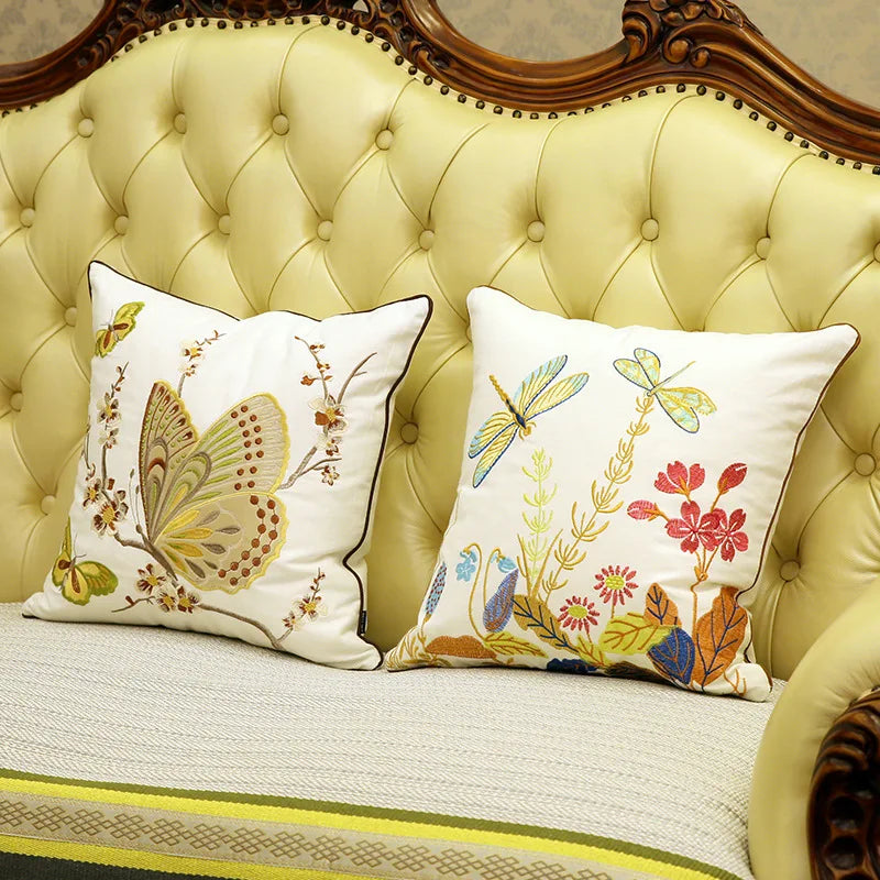 Une pièce de mobilier élégante avec des coussins décoratifs illustrés de motifs floraux et de papillons, créant une atmosphère chaleureuse et raffinée.