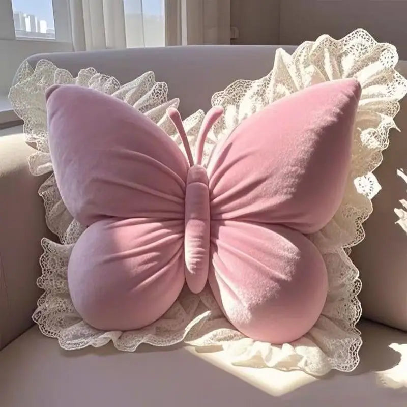 Coussin décoratif en forme de papillon rose avec dentelle blanche, idéal comme oreiller d'appoint ou élément de décor dans un intérieur féminin et romantique.