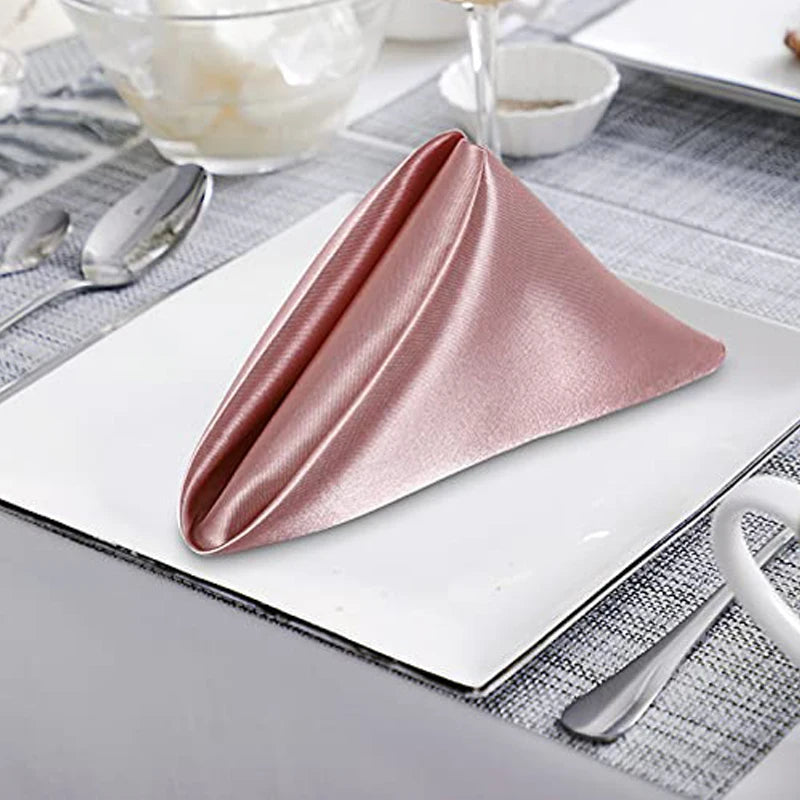 Serviette pliée en satin rose posée sur une table.