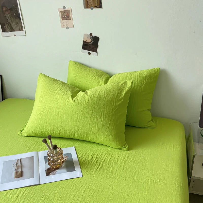 Ensemble de literie vert citron avec des coussins et des éléments décoratifs posés sur le lit.