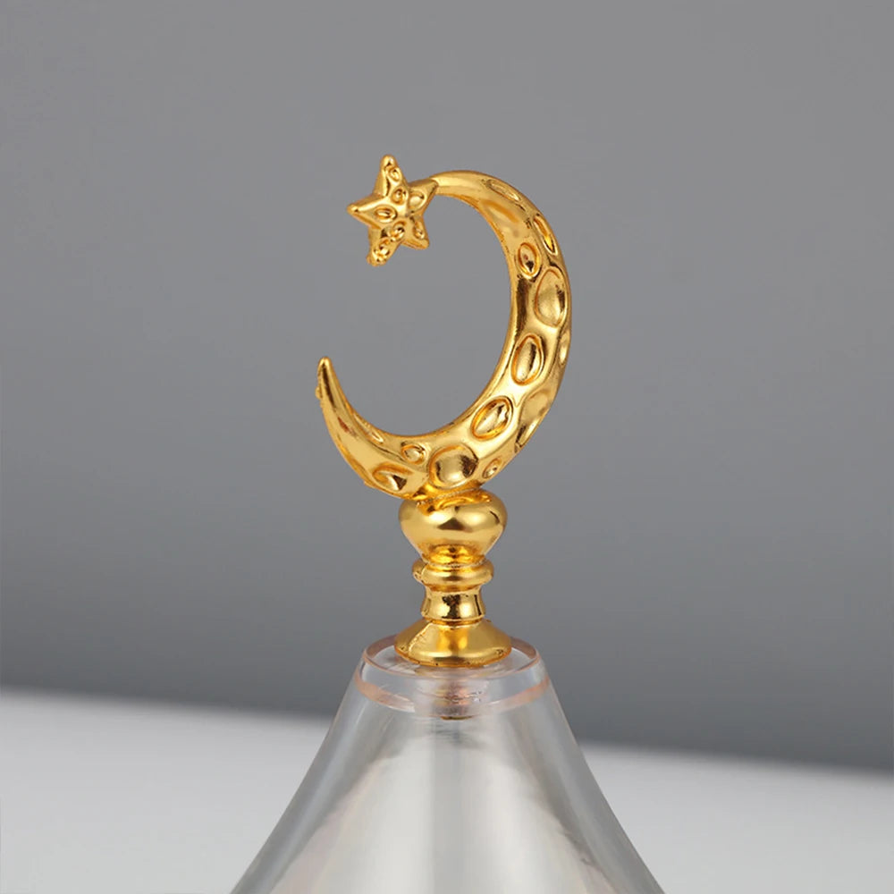 Décorative figurine en forme de lune dorée avec une étoile, montée sur un support en verre.