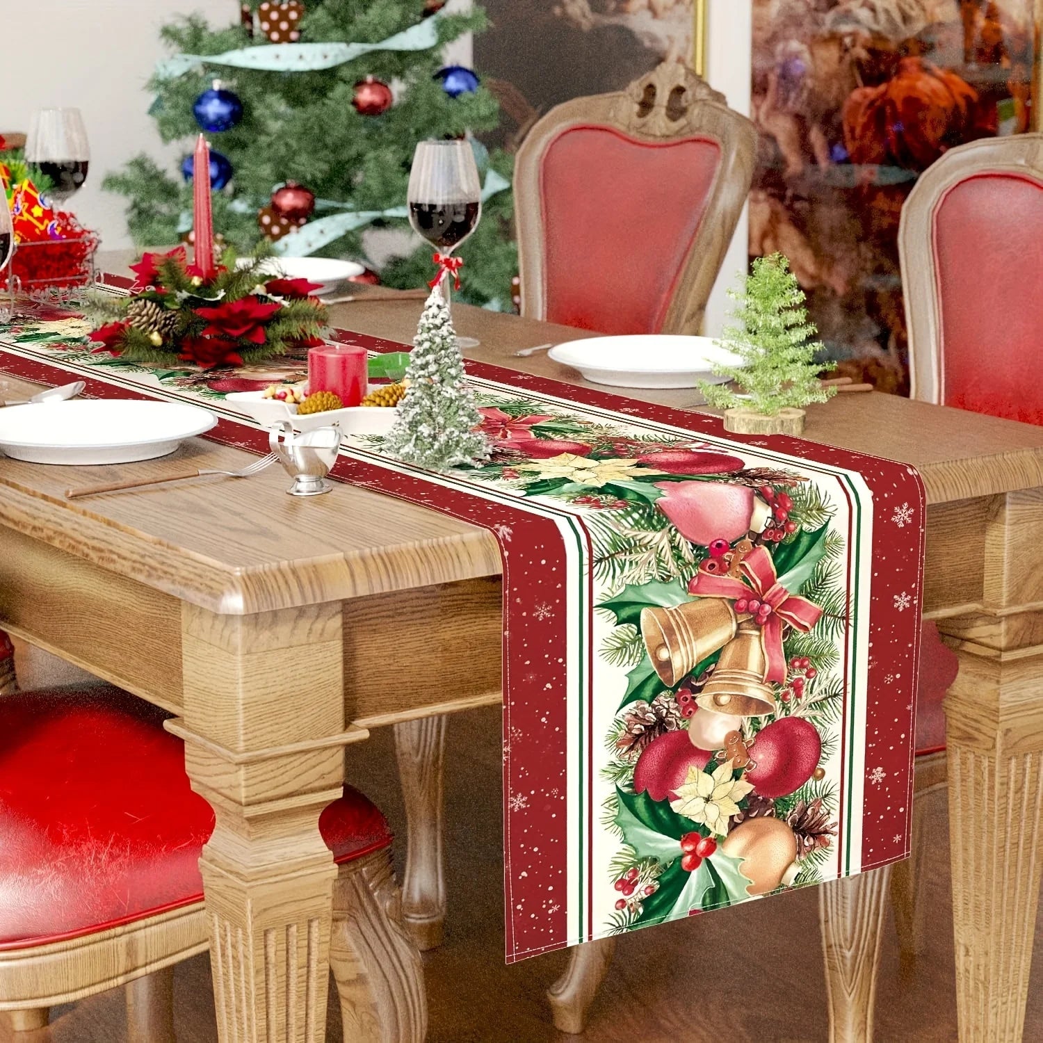 Une table de Noël décorée avec un chemin de table coloré, des bougies rouges, des ornements et un petit arbre de Noël.