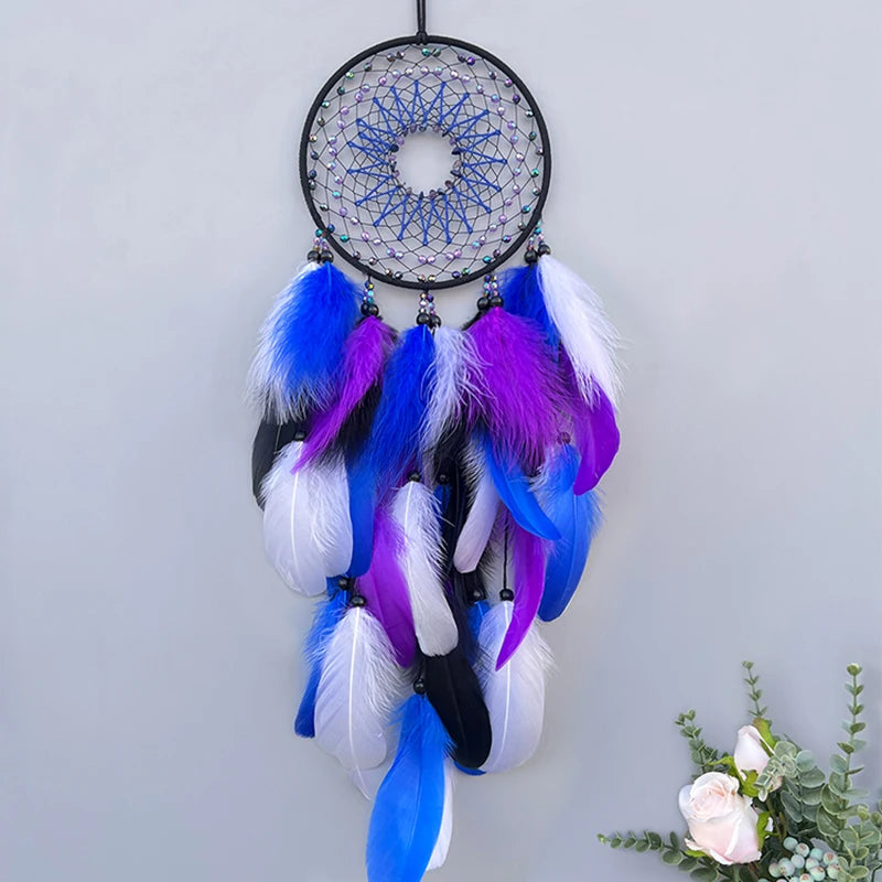 Un capteur de rêves orné de plumes colorées bleues et violettes, suspendu sur un fond gris.