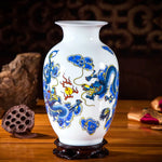 Vase en porcelaine blanche décoré de motifs de dragons et de fleurs stylisées dans des tons de bleu et rouge sur un fond sombre.