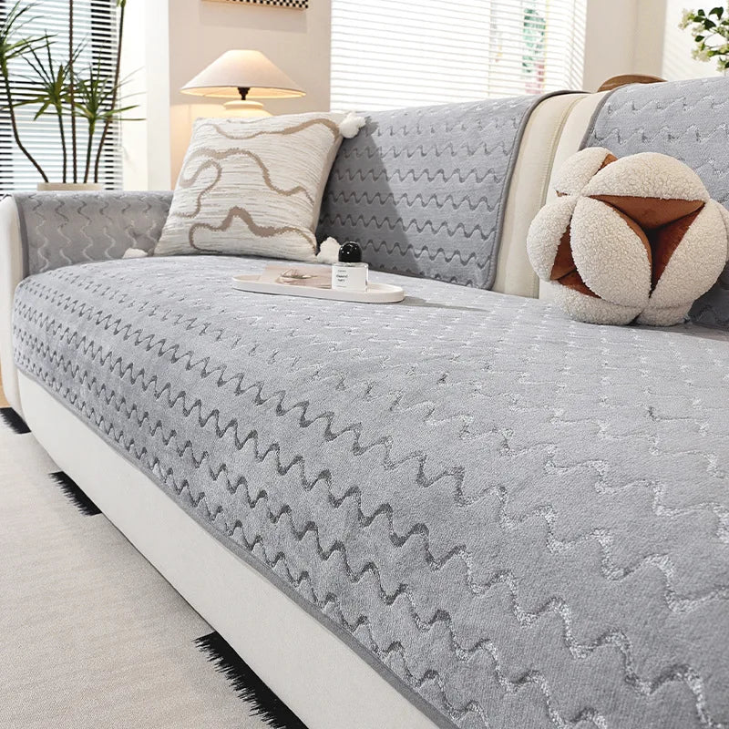 Un canapé gris moelleux et confortable avec des coussins décoratifs et un ours en peluche, créant une atmosphère chaleureuse et accueillante dans cette pièce.