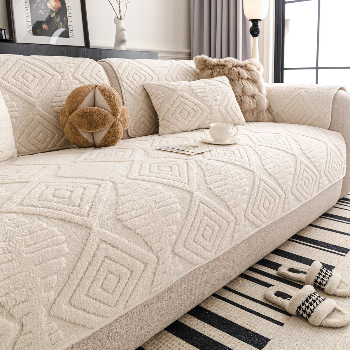 Canapé douillet et confortable avec des motifs géométriques texturés, une tasse de thé posée sur le côté et des accessoires en fourrure apportant une ambiance cocooning à l'espace.