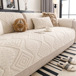 Canapé douillet et confortable avec des motifs géométriques texturés, une tasse de thé posée sur le côté et des accessoires en fourrure apportant une ambiance cocooning à l'espace.