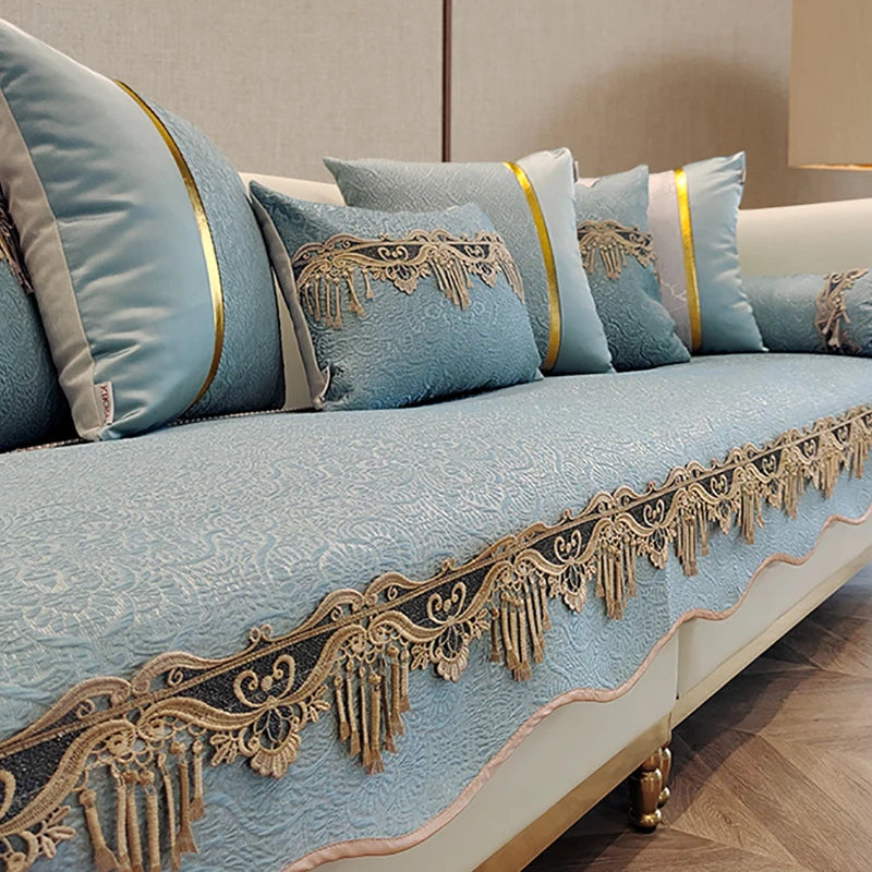 Un canapé douillet et élégant dans des tons bleu clair et dorés, avec des motifs décoratifs et des franges qui lui confèrent une touche de raffinement.