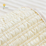 Gros plan sur le motif plissé d'un tissu doux et délicat de couleur crème.