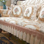 Élégant canapé d'angle capitonné beige et doré avec des motifs floraux, des bordures ornées et des coussins décoratifs.