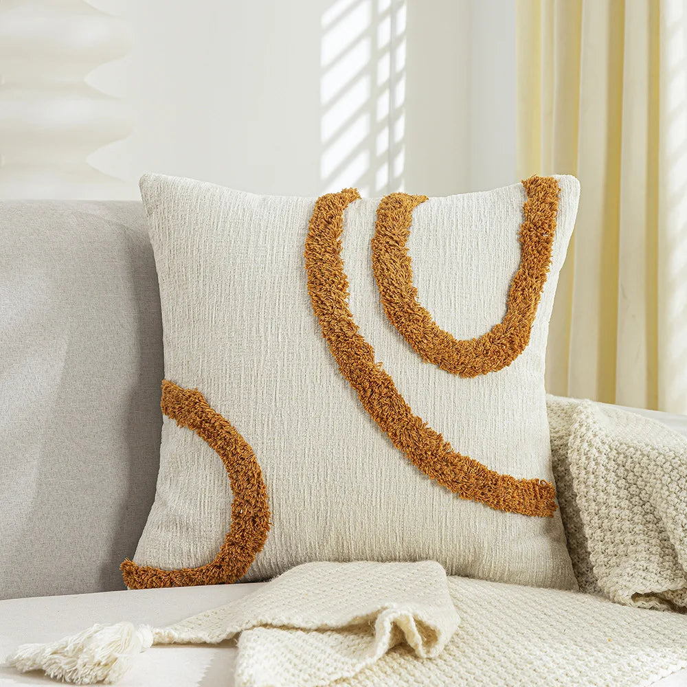 Coussin décoratif crème et ocre avec motif ondulé texturé.