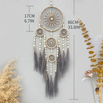 Rêve attrapeur décoratif suspendu aux motifs entrelacés et aux plumes grises.