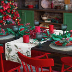 Une belle table de Noël avec des décorations rouges et vertes, des bougies allumées et des verres élégants sur un fond de vaisselle et d'étagères en bois.