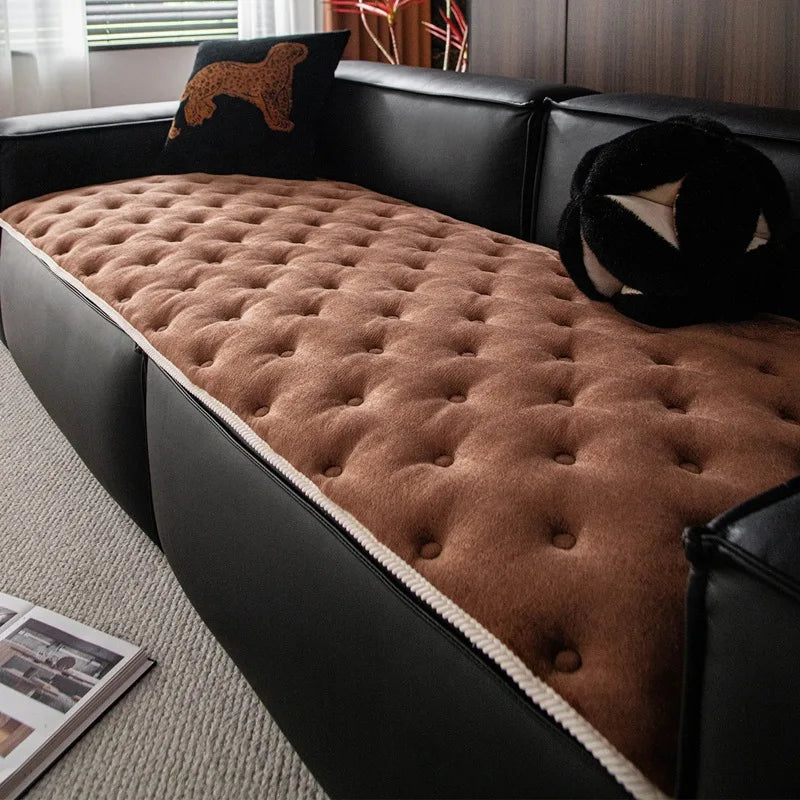 Un canapé en cuir noir avec un coussin moelleux en velours marron et quelques décorations animales, dans un intérieur confortable et douillet.