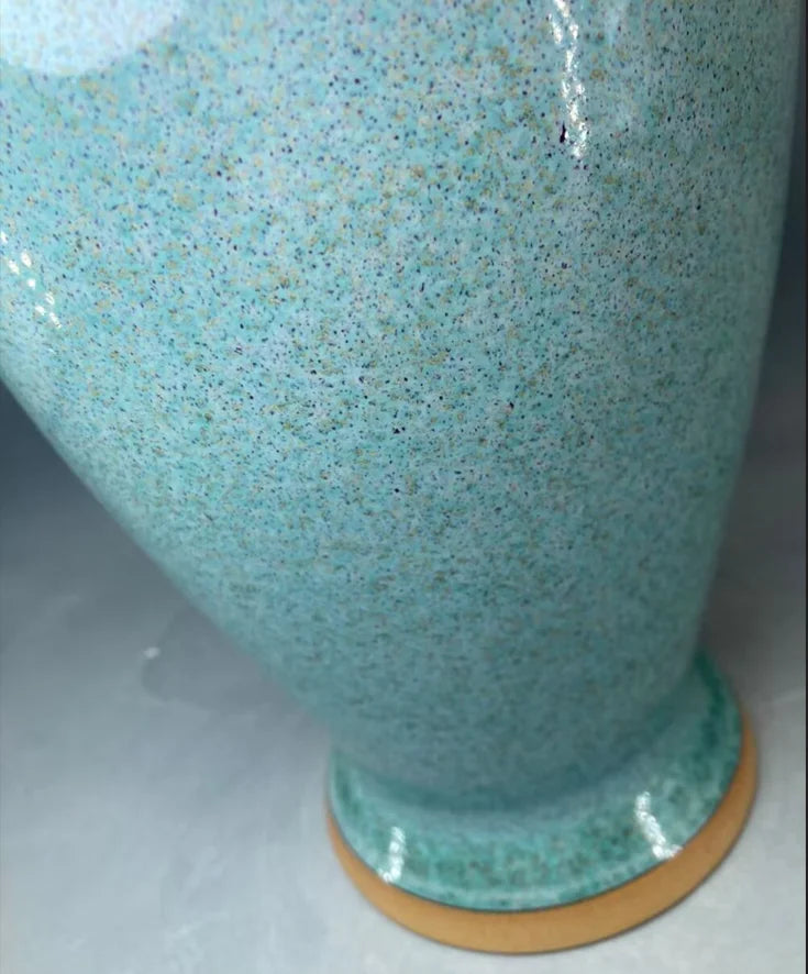 Vase en céramique de couleur turquoise avec des éclats et des accents dorés.