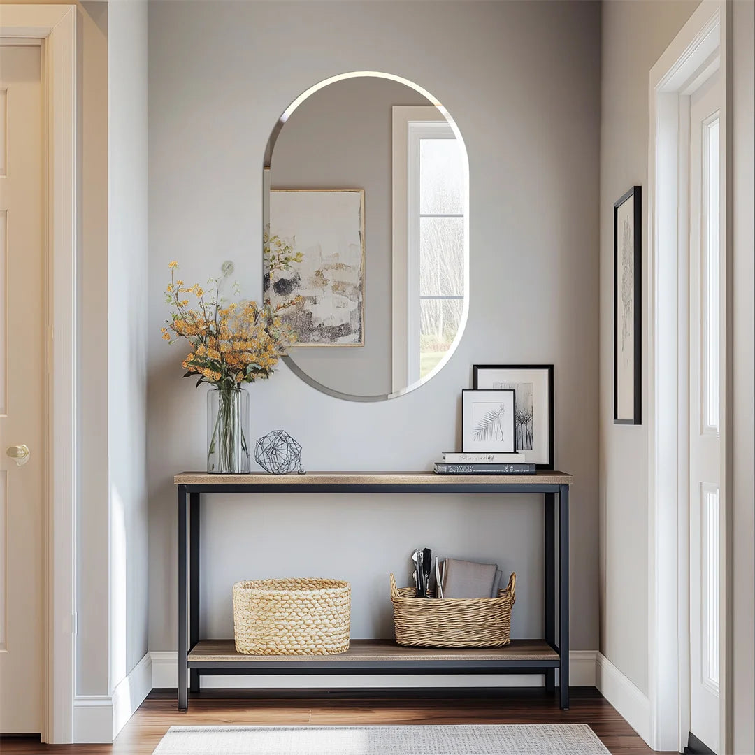 Un meuble d'entrée élégant avec un miroir ovale, un cadre décoratif et des paniers en osier, créant une ambiance accueillante et bien organisée dans ce hall d'entrée.