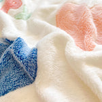 Cette image montre une pile de vêtements doux et moelleux de différentes couleurs, notamment du blanc, du bleu et du rose, formant une texture douce et confortable.