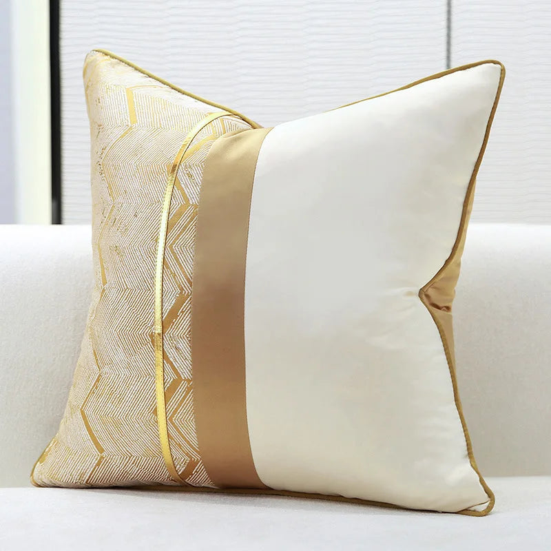 Un coussin décoratif élégant, avec des motifs géométriques dorés sur un fond blanc, conçu pour apporter une touche raffinée à un intérieur.