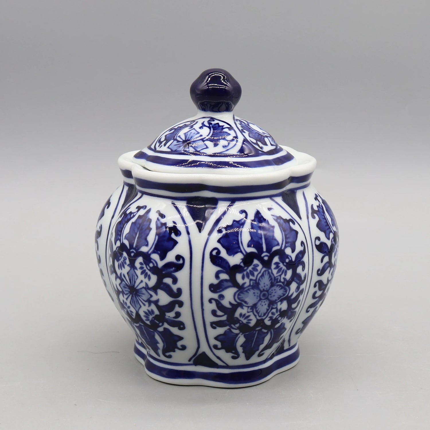 Superbe pot de céramique de style oriental décoré de motifs floraux et de rayures bleues et blanches, avec un couvercle en forme de sphère.