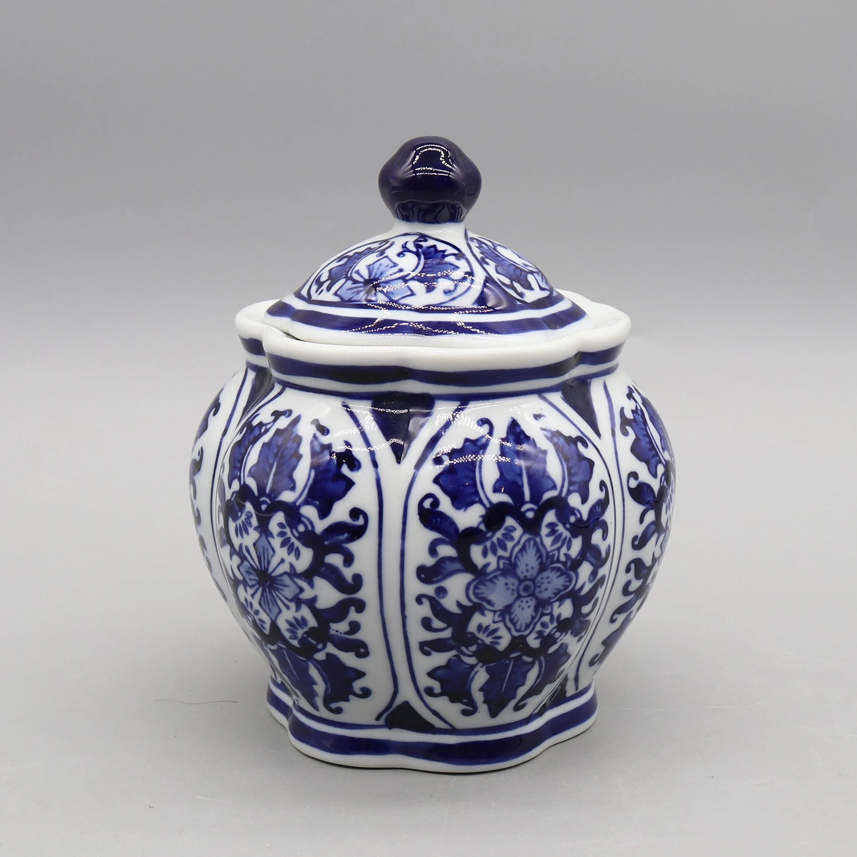 Superbe pot de céramique de style oriental décoré de motifs floraux et de rayures bleues et blanches, avec un couvercle en forme de sphère.