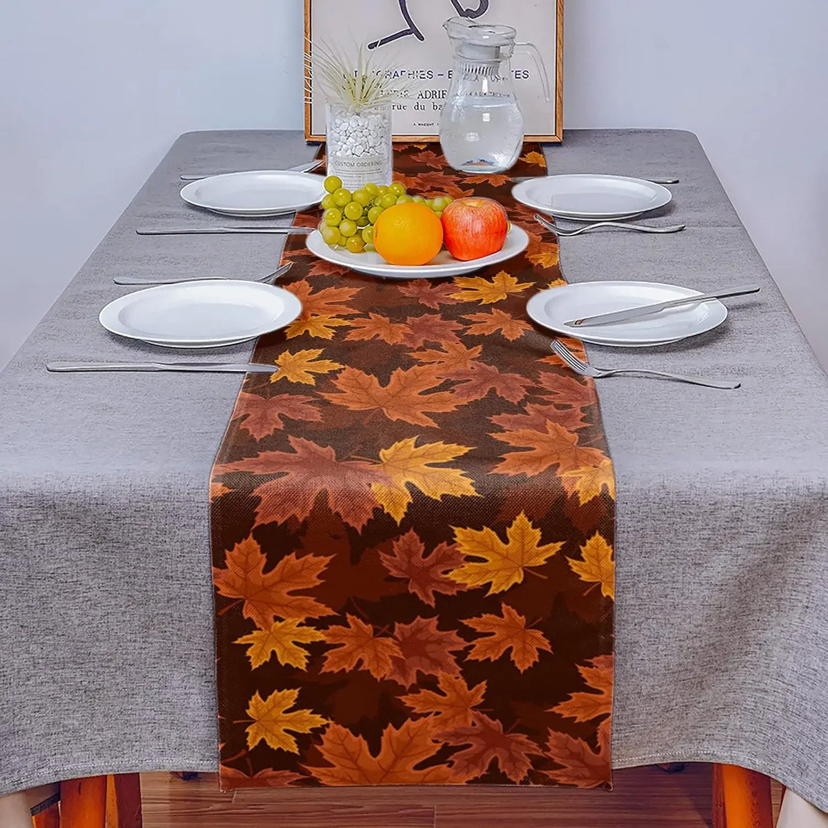 Élégante table d'automne avec un chemin de table motif feuilles d'érable et une assiette de fruits.