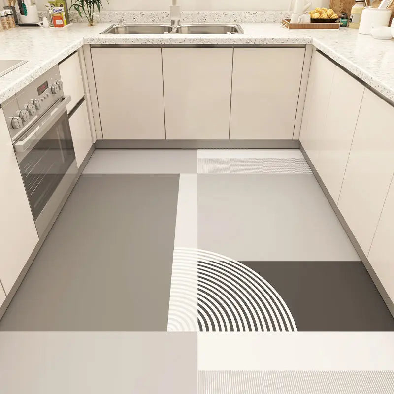 Cette image montre une cuisine moderne avec des comptoirs en pierre de granit blanc et des armoires beige, ainsi qu'un motif graphique en noir et blanc sur le sol en carrelage.