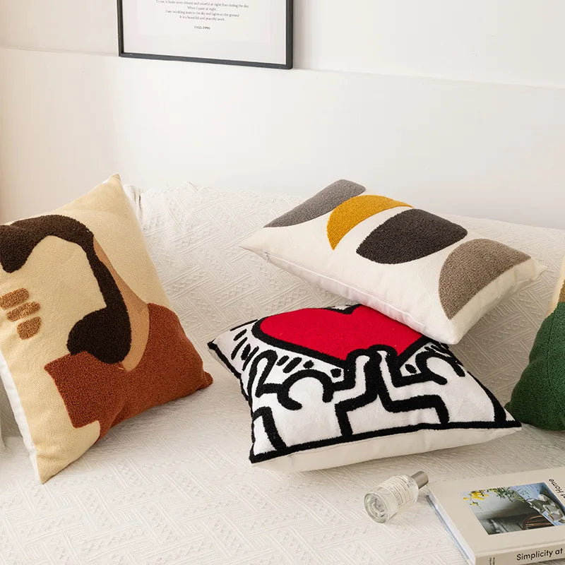 Une collection de coussins décoratifs avec des motifs géométriques, des formes abstraites et des couleurs vives, créant une ambiance moderne et épurée dans cette pièce.