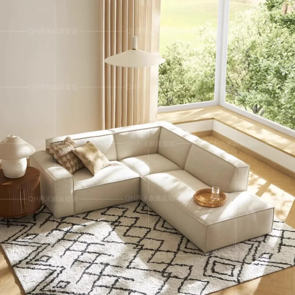 canapé d'angle moderne beige clair uni confortable salon minimaliste inclusion coussins tapis