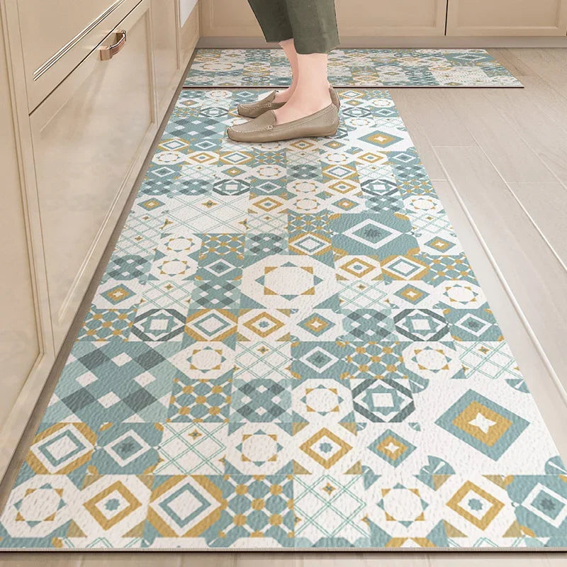Tapis aux motifs géométriques bleutés et dorés recouvrant le sol d'une cuisine, avec les pieds de la personne portant des chaussures en suède claires.