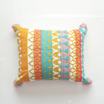 Coussin décoratif coloré avec des motifs géométriques et des franges.