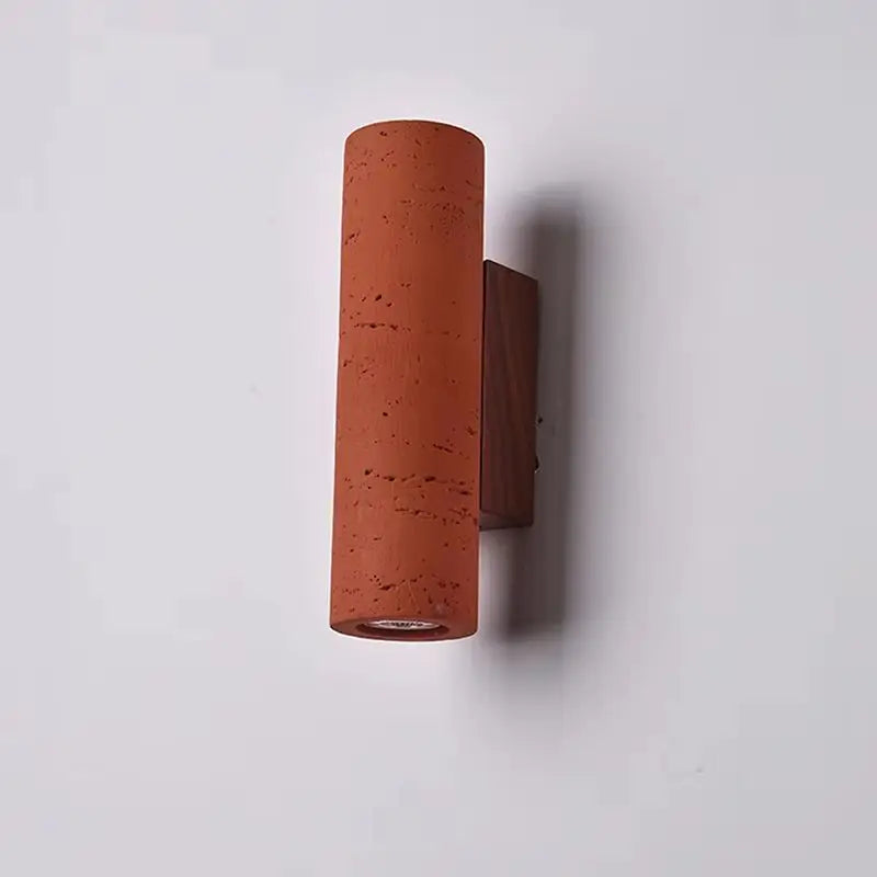 Applique murale cylindrique en pierre rouge corail installée dans un couloir