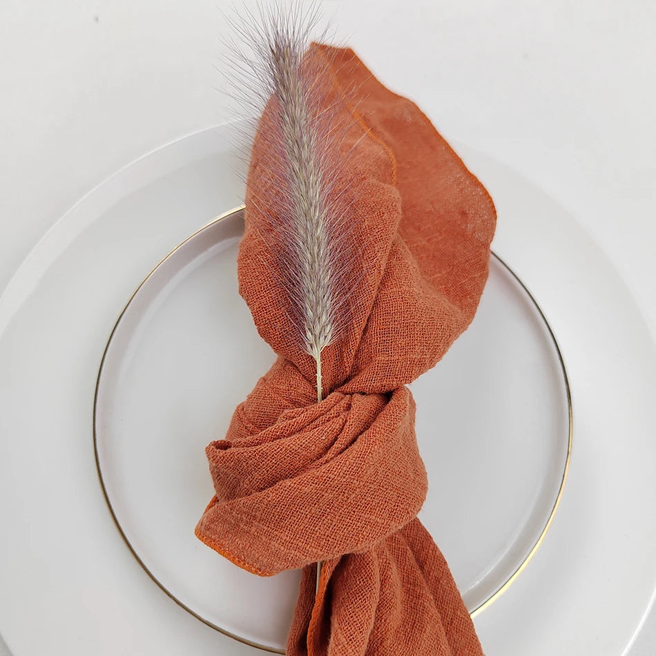 Un châle brun enroulé autour d'une plume grise élégante, posé sur une assiette blanche.