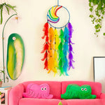 Un magnifique capteur de rêves multicolore suspendu au mur, entouré de plantes et d'un canapé rose animé décoré de coussins en forme de créatures fantastiques.