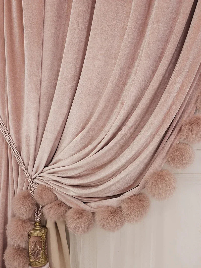 Rideau rose poudré attaché sur le côté avec embrasse, orné de pompons au bas pour une finition élégante et romantique.