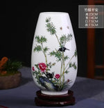 Vase en porcelaine blanc avec motif de plantes et d'insectes peints délicatement, créant une scène naturelle élégante et apaisante.
