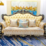 Un canapé baroque en cuir doré avec des coussins ornés de motifs floraux, surmonté d'une toile abstraite aux teintes chatoyantes, créant une atmosphère luxueuse et raffinée.