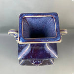Petit vase cubique en céramique bleue avec décoration dorée.