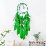 Un rêve crée en vert, un capteur de rêves en plumes vertes et perles décoratives suspendu au mur, rehaussé de petits détails qui apportent une touche apaisante et naturelle à l'environnement.