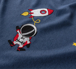 T-shirt pour enfants avec motif astronaute et fusée colorée, sur fond bleu. Style ludique et original idéal pour les jeunes passionnés d'espace et de découvertes interstellaires. Parfait pour apporter une touche de fantaisie à la garde-robe des petits aventuriers.