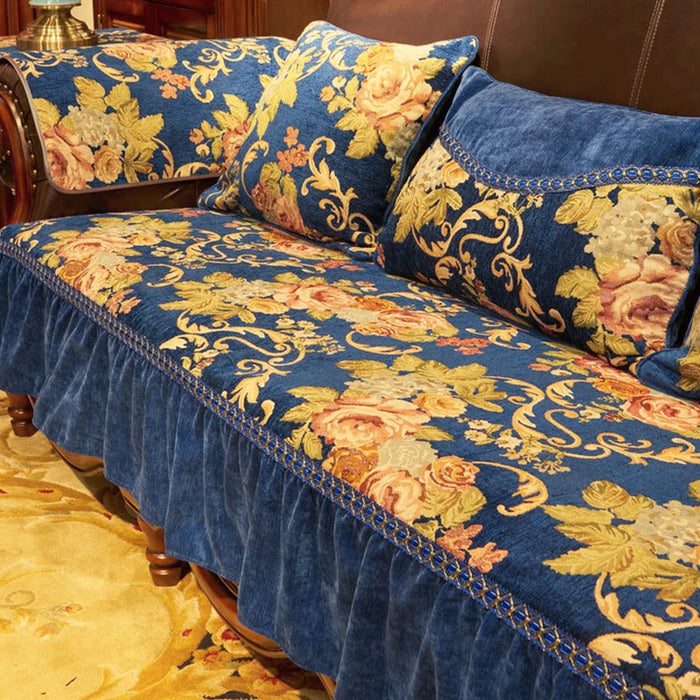 Canapé rembourré décoré de motifs floraux dorés et bleus sur un fond bleu foncé, orné de galons et franges, évoquant un style baroque élégant.