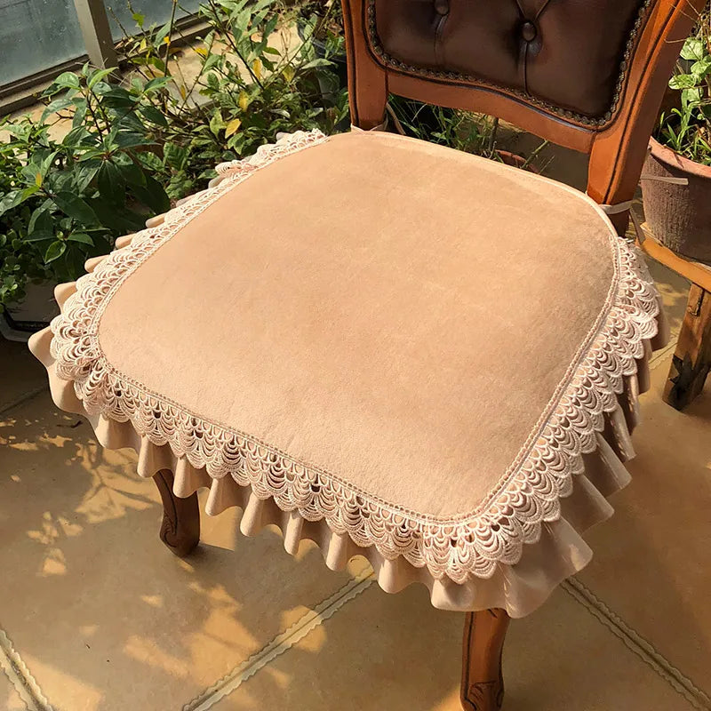 Chaise ancienne en bois avec un coussin beige orné d'une jolie dentelle dans un environnement de plantes vertes.