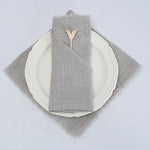 Assiette blanche avec serviette de table grise et petite décoration en métal.