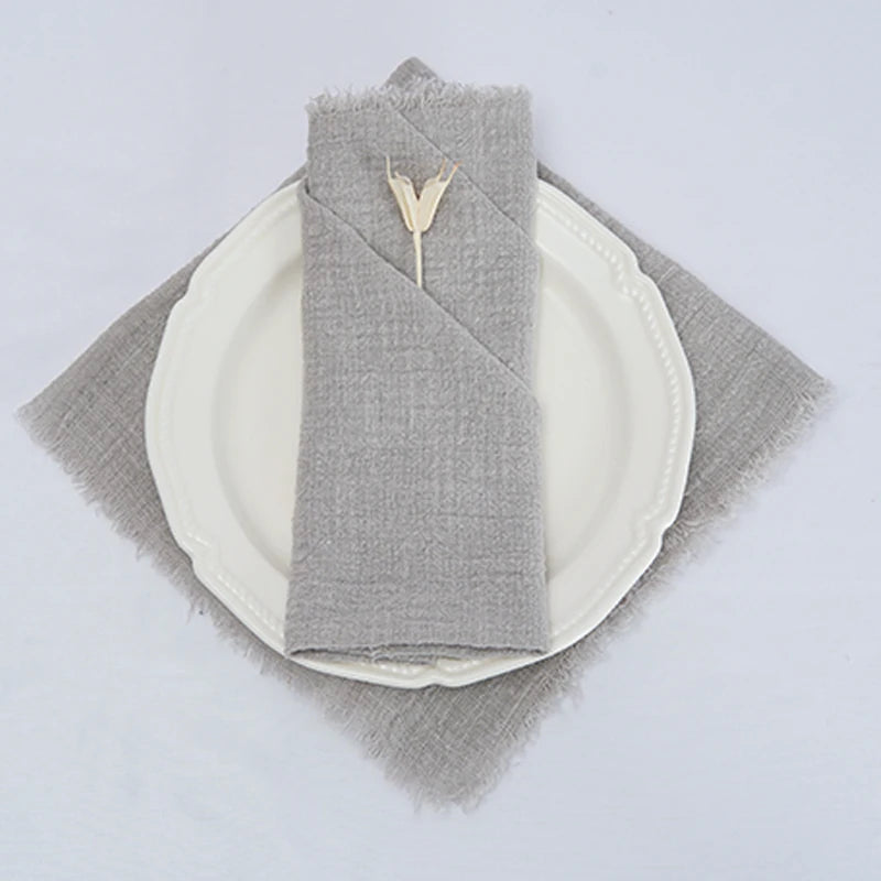 Assiette blanche avec serviette de table grise et petite décoration en métal.