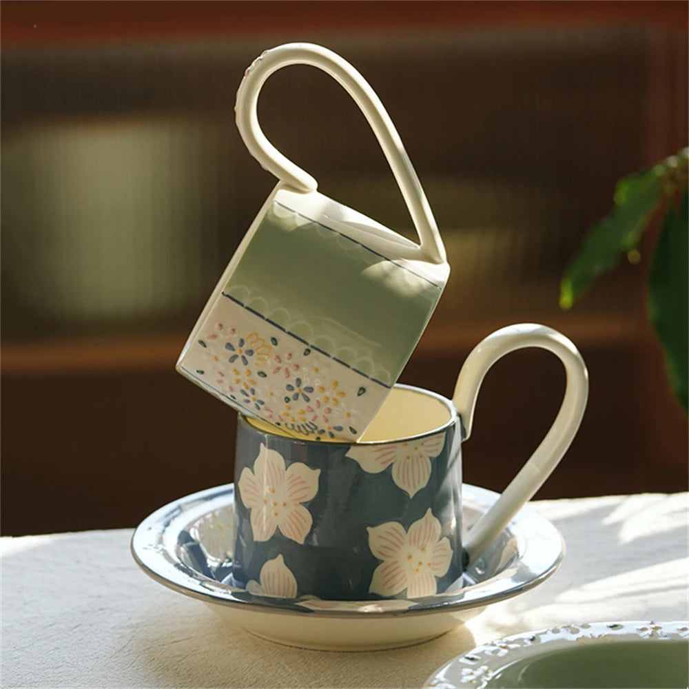 Une tasse et sous-tasse décorées de fleurs et motifs colorés sur fond sombre et bois clair, évoquant une ambiance élégante et charmante.