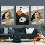 L'image affiche trois tableaux d'art abstrait représentant des formes organiques et géométriques dans des tons de terre et de noir, créant une atmosphère apaisante et moderne dans cet intérieur.