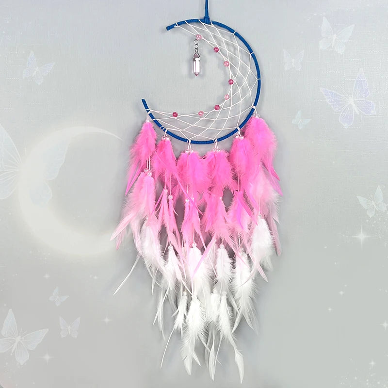 Capteur de rêves décoratif en forme de lune avec des plumes roses et blanches, un cadre bleu et des perles pendant.