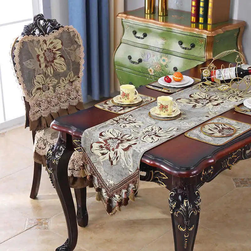 Une table vintage ornée de nappes et de décorations florales, avec un meuble vintage en bois peint en vert agrémenté de motifs.