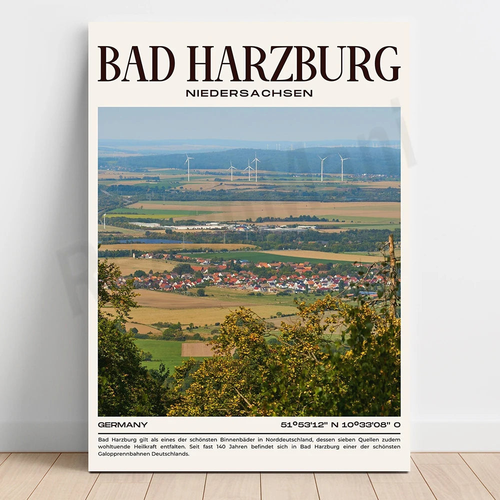 Un paysage vallonné avec un village pittoresque, des champs cultivés et des éoliennes à l'horizon, représentant la ville de Bad Harzburg dans la région de Basse-Saxe en Allemagne.