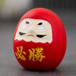statuette japonaise daruma rouge or visage stylisé sourcils yeux barbe blanche traditionnelle décoration maisonporte