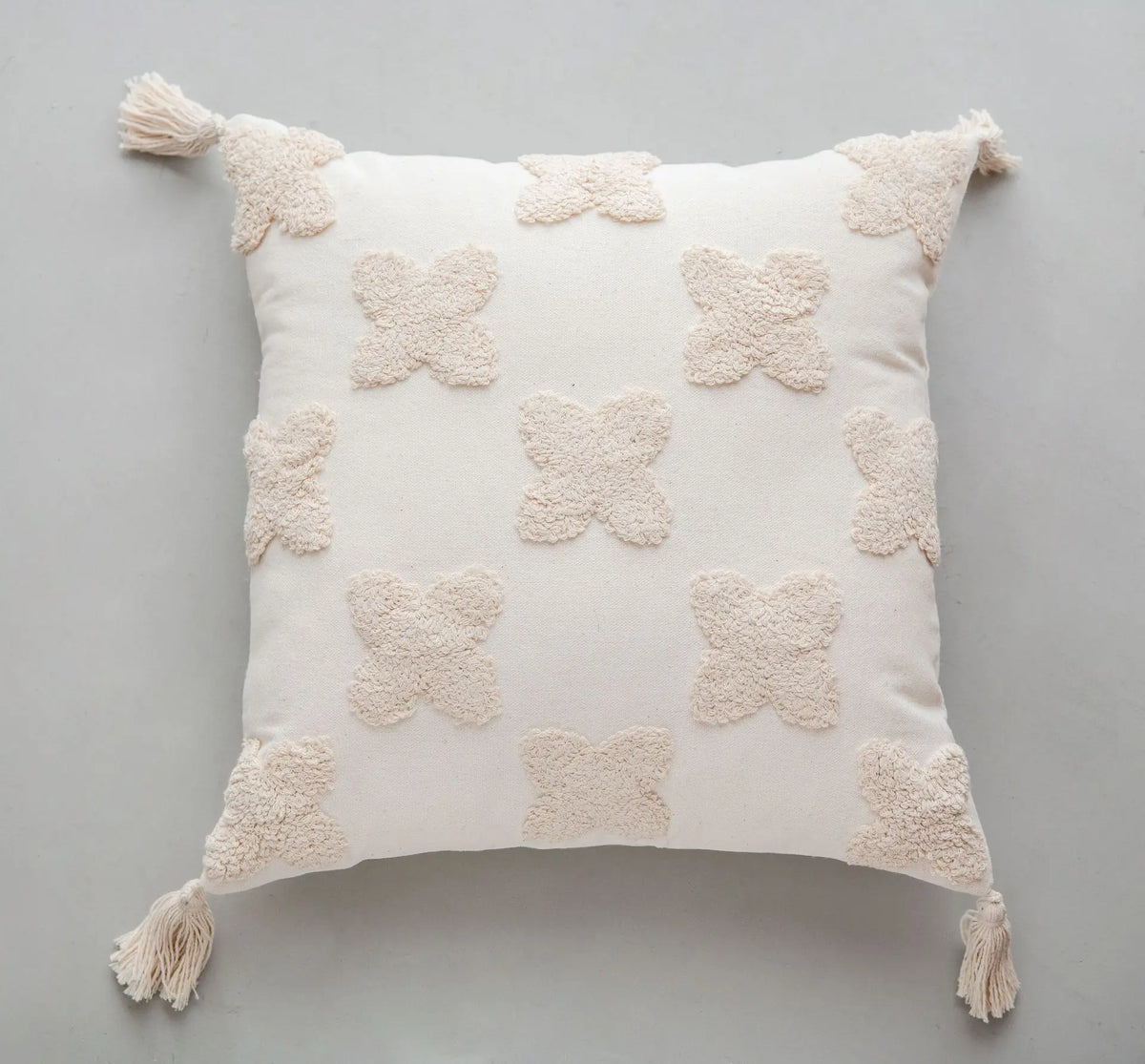 Coussin décoratif blanc en forme de fleurs avec pompons aux coins.